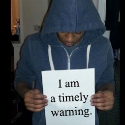 Young man holding "I am a timely warning" sign