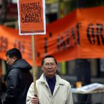 Man holding sign protesting agent orange