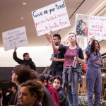 photo of crowd protesting Richard Spencer talk; people holding protest signs, stating on tables inside of an academic building.