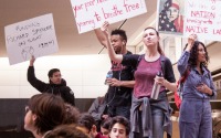 photo of crowd protesting Richard Spencer talk; people holding protest signs, stating on tables inside of an academic building.